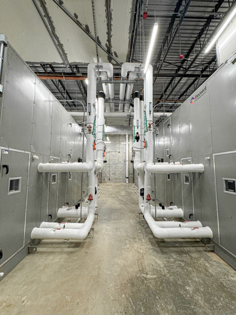 Two air handler units (AHU)installed in a mechanical room, connected to supply and return ductwork for efficient air distribution